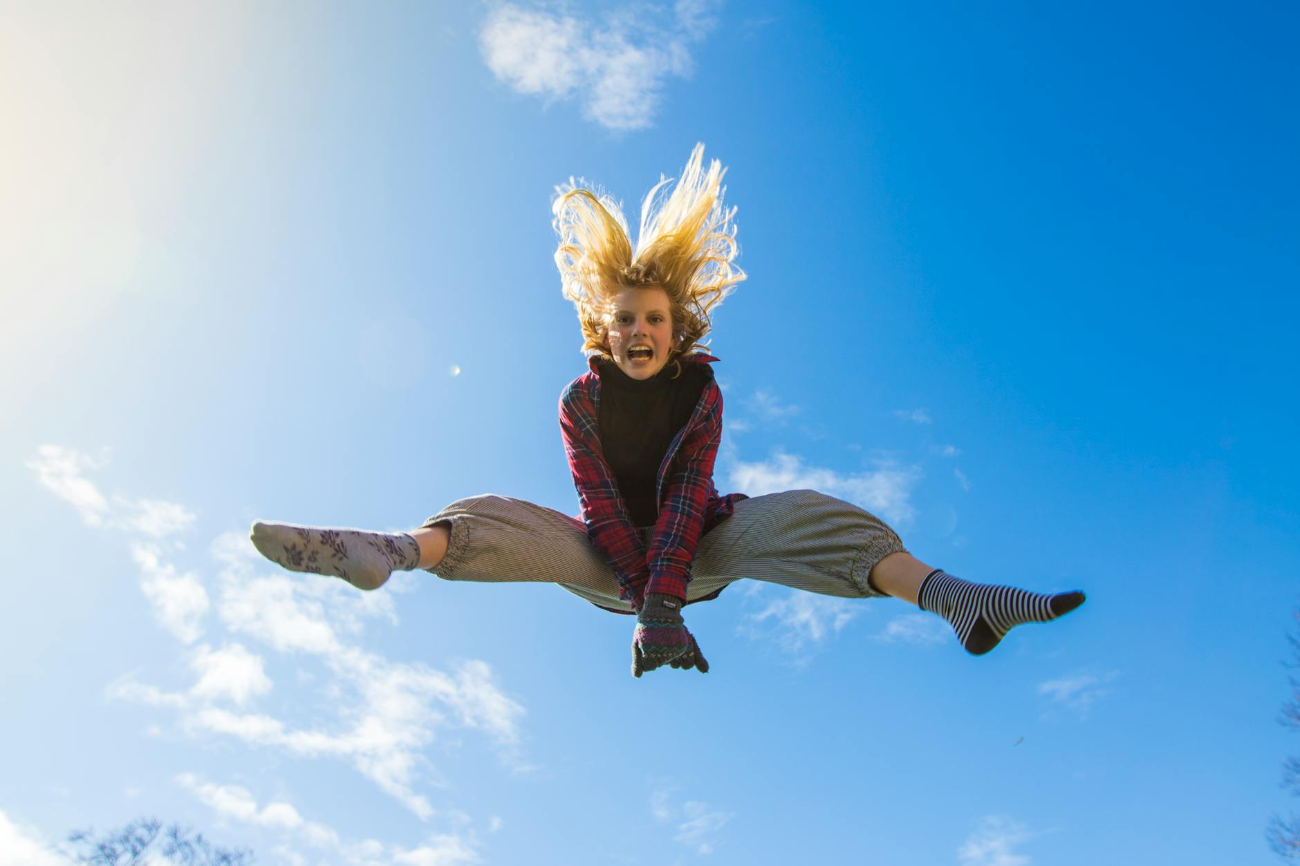 woman jumping under blue sky