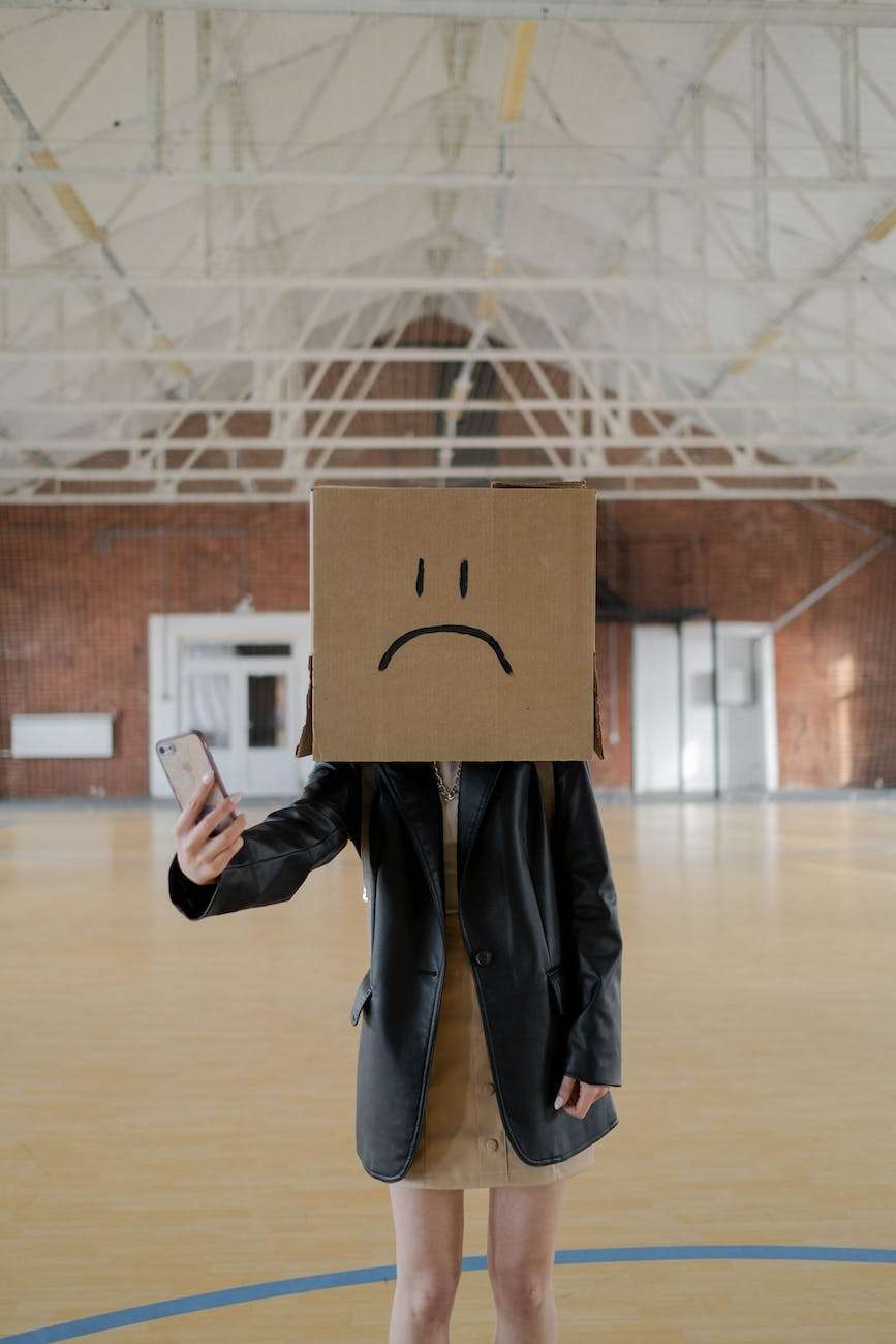 person with head covered with a cardboard box taking a selfie