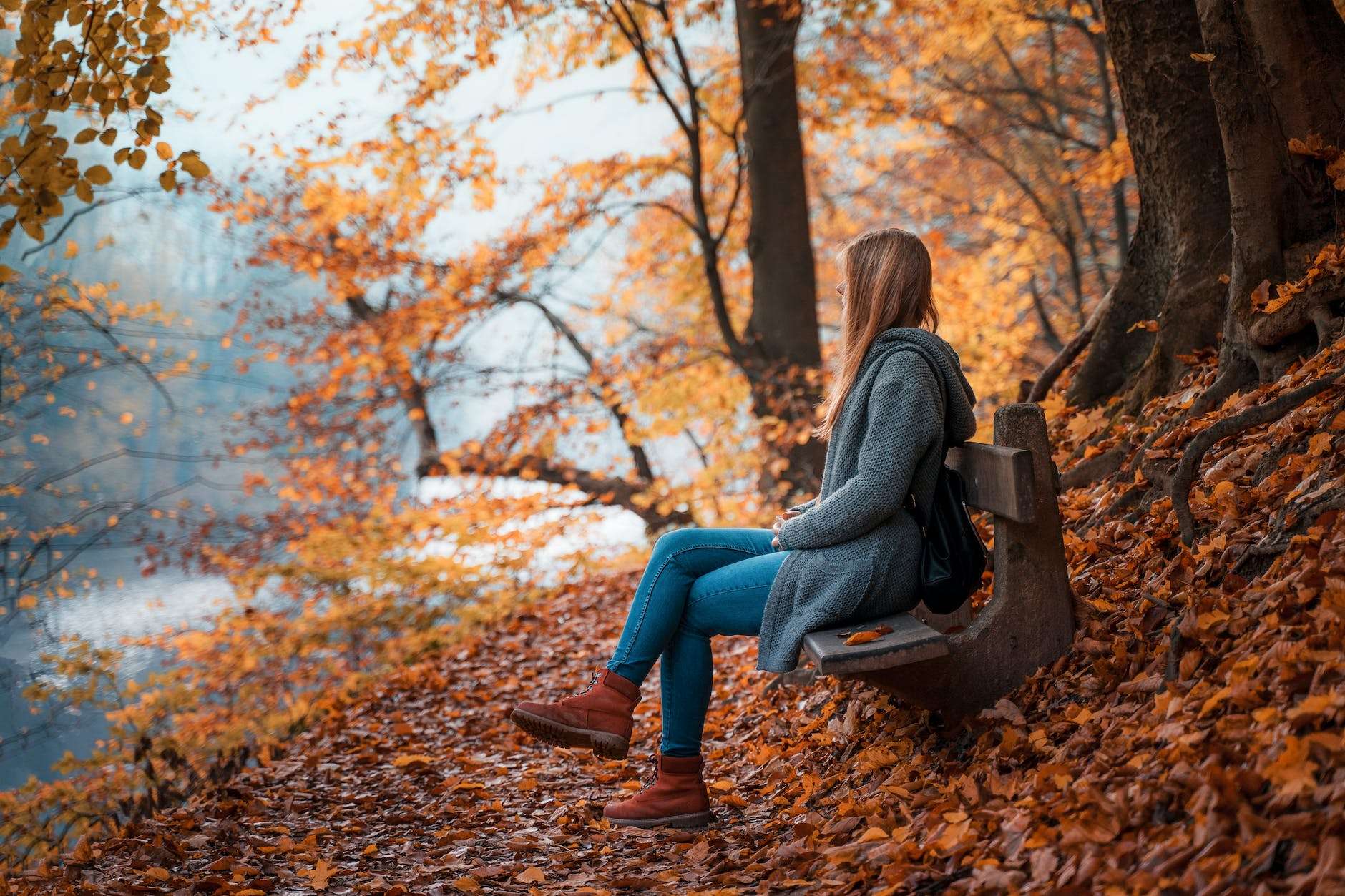 photo of woman sitting on wooden bench