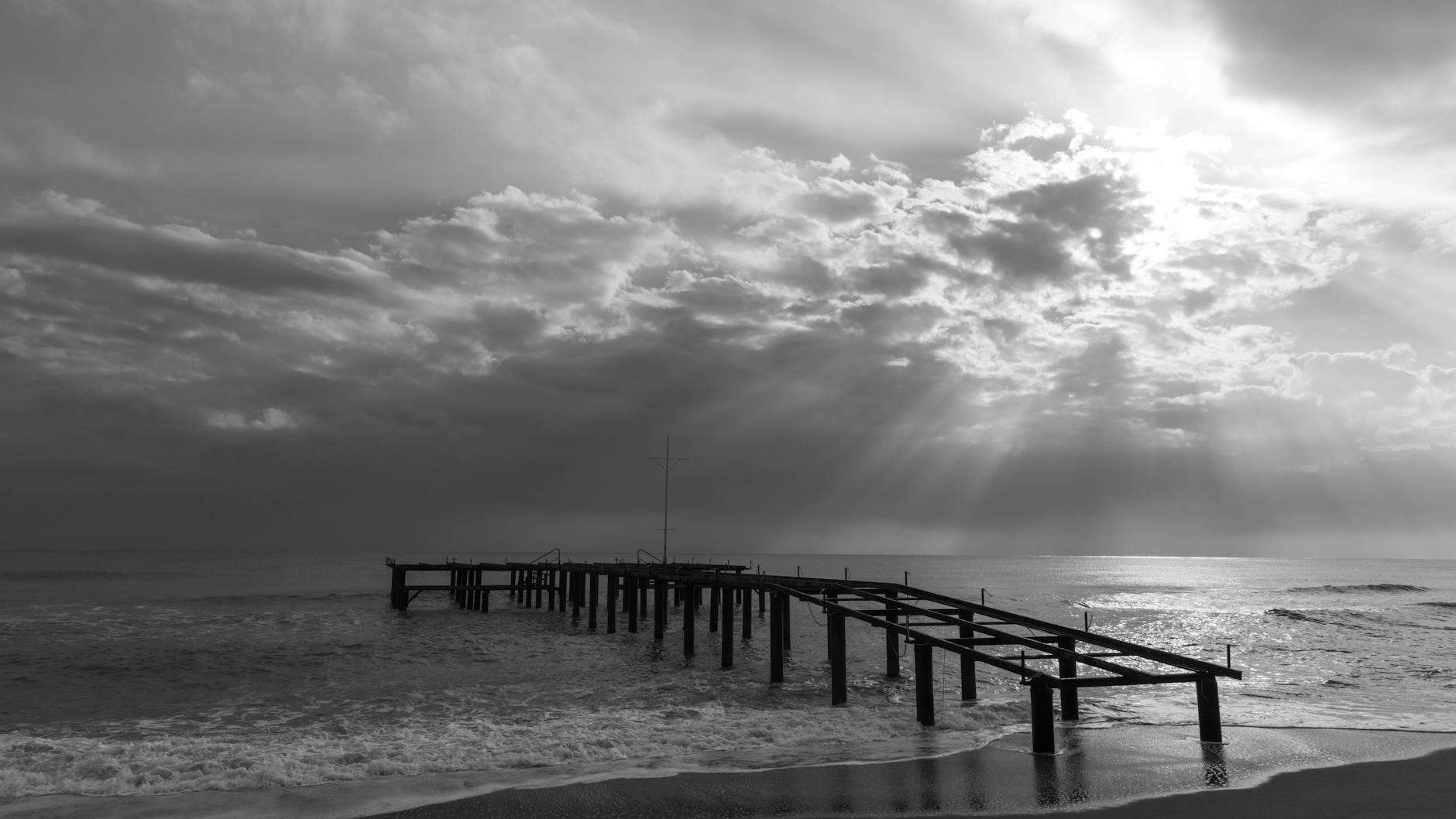 grayscale photo of an old and broken down wooden boardwalk on sea