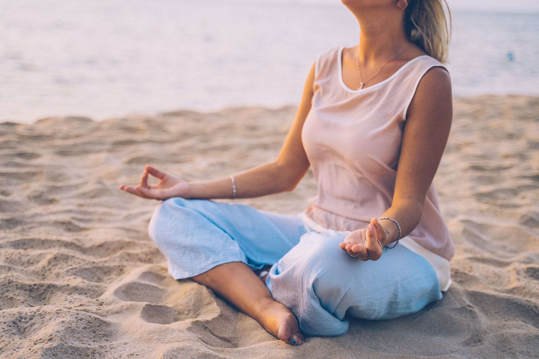woman sitting on sand while doing yoga