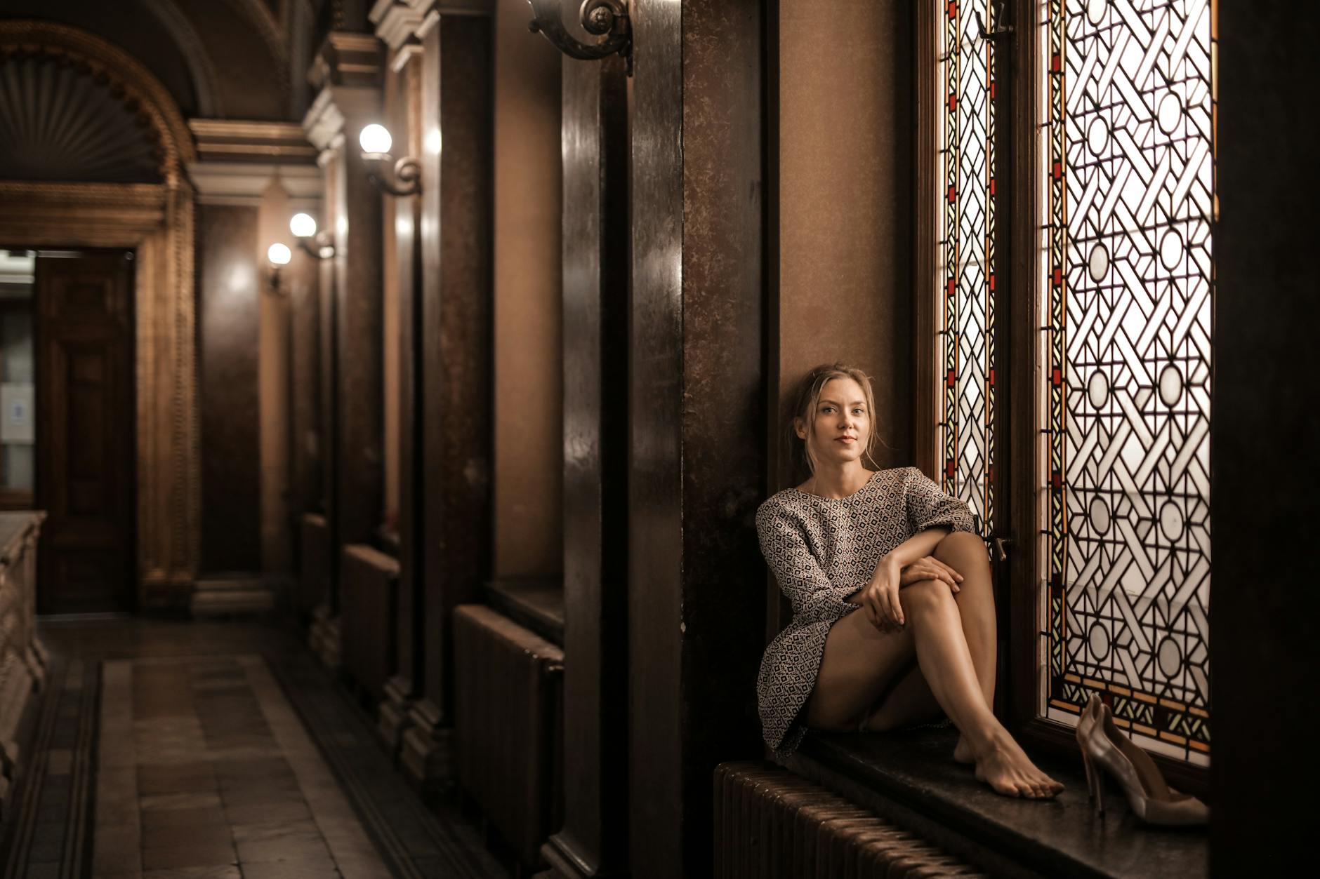 young lady sitting on window sill in hall