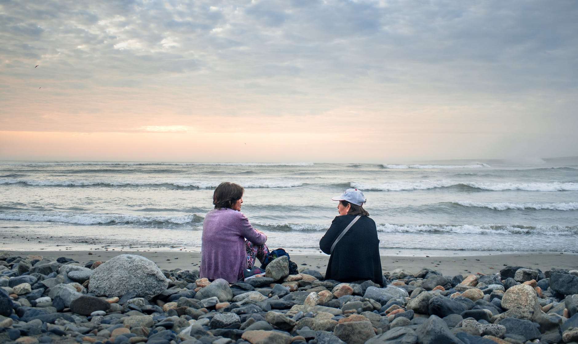 women sitting on the shore