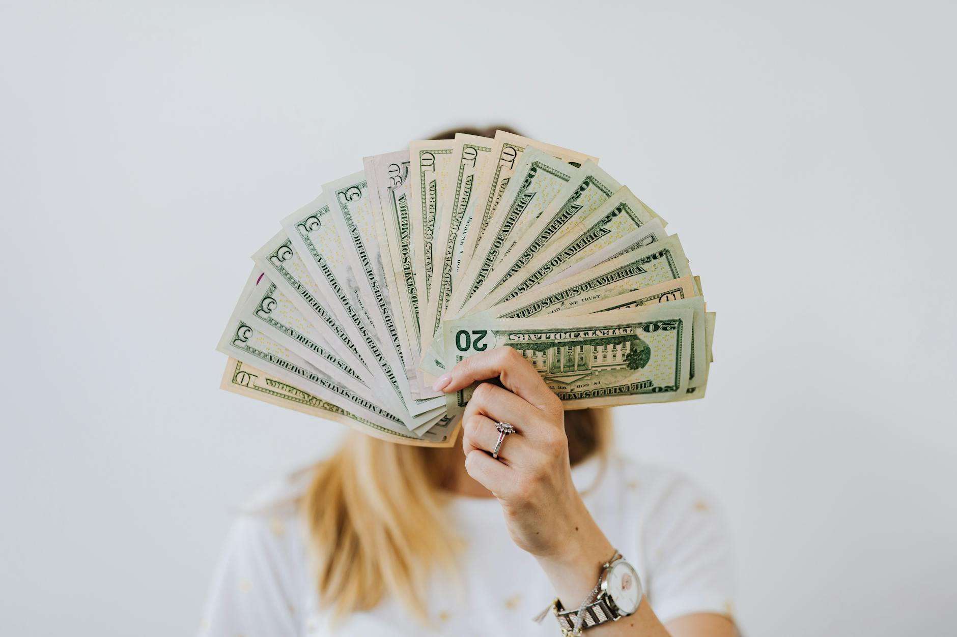 woman holding fan of us dollar bills