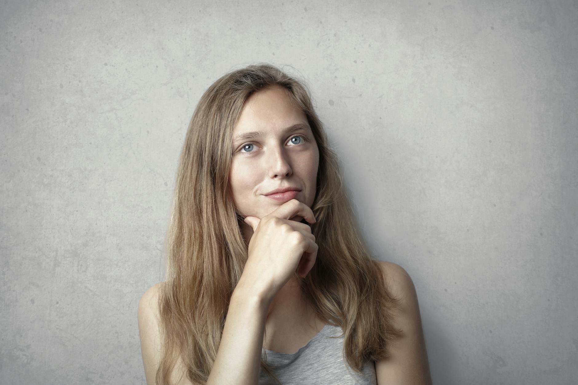 woman in gray tank top while holding her chin