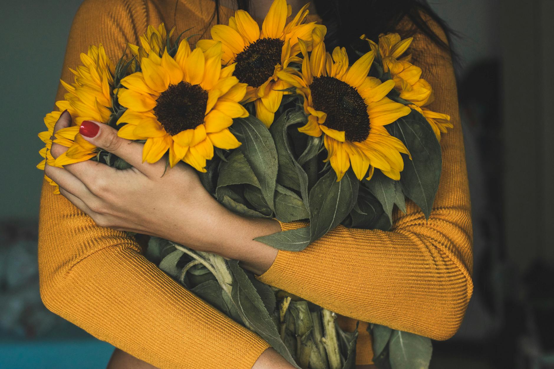 woman holding bunch of sunflowers