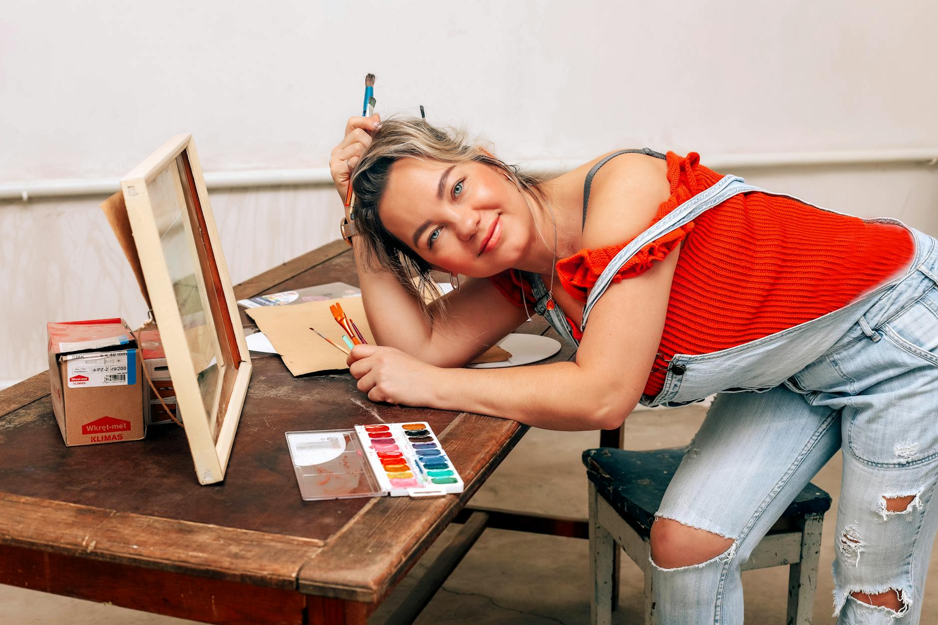 smiling blonde woman leaning on table and painting
