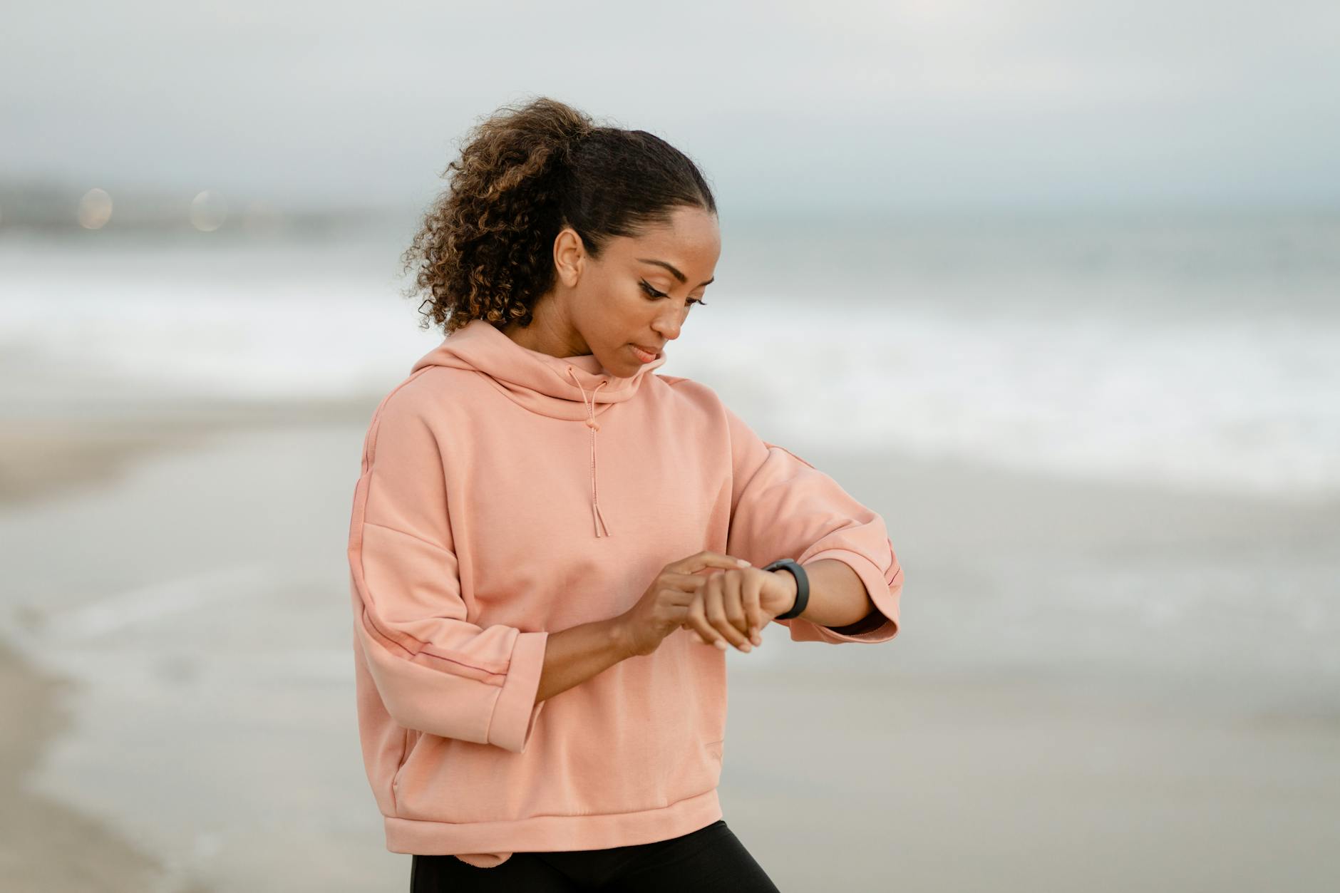 woman in pink jacket looking at her watch