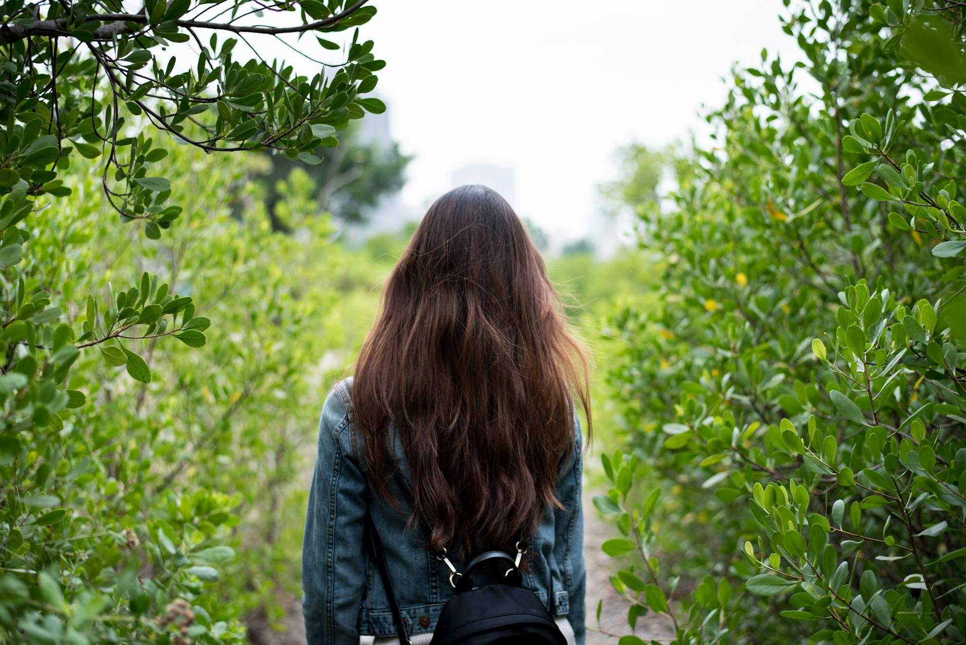 woman in gray denim jacket in the middle of bushes