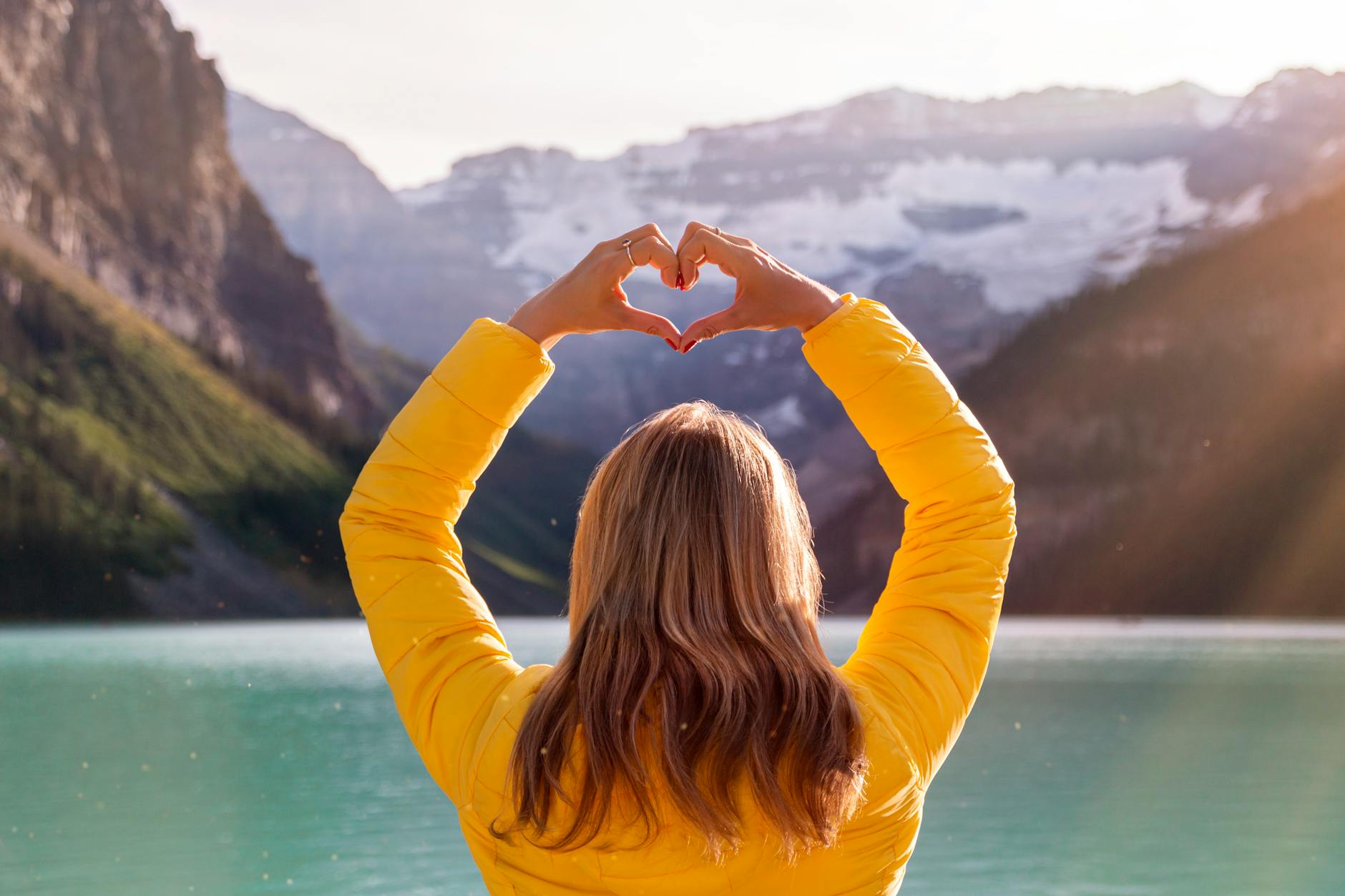 back view of woman in yellow long sleeve shirt with heart hand gesture