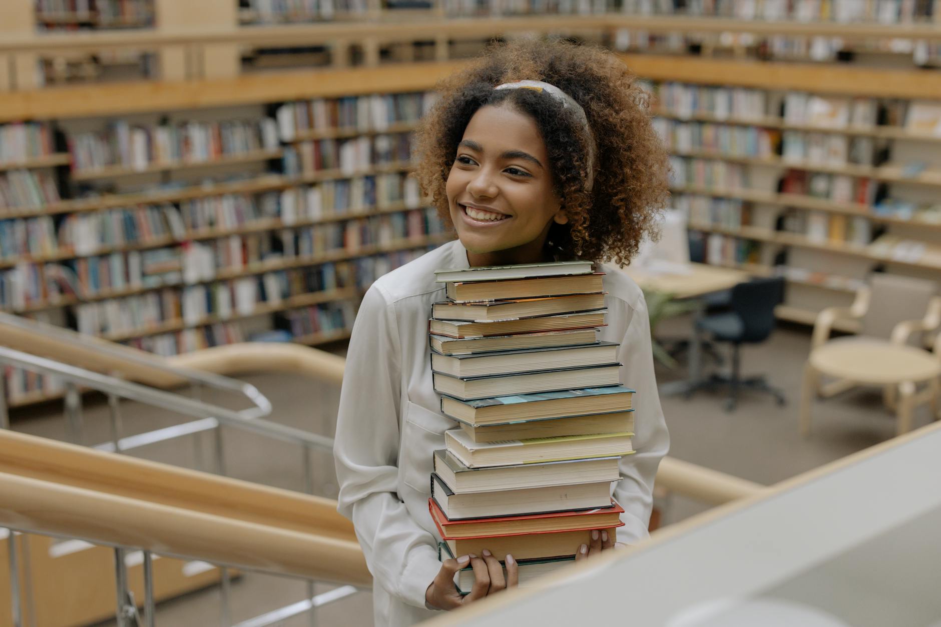 photo of woman carrying stack of books