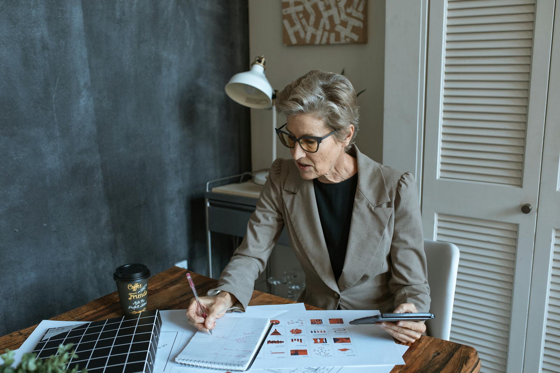 focused businesswoman writing in notebook during work in office