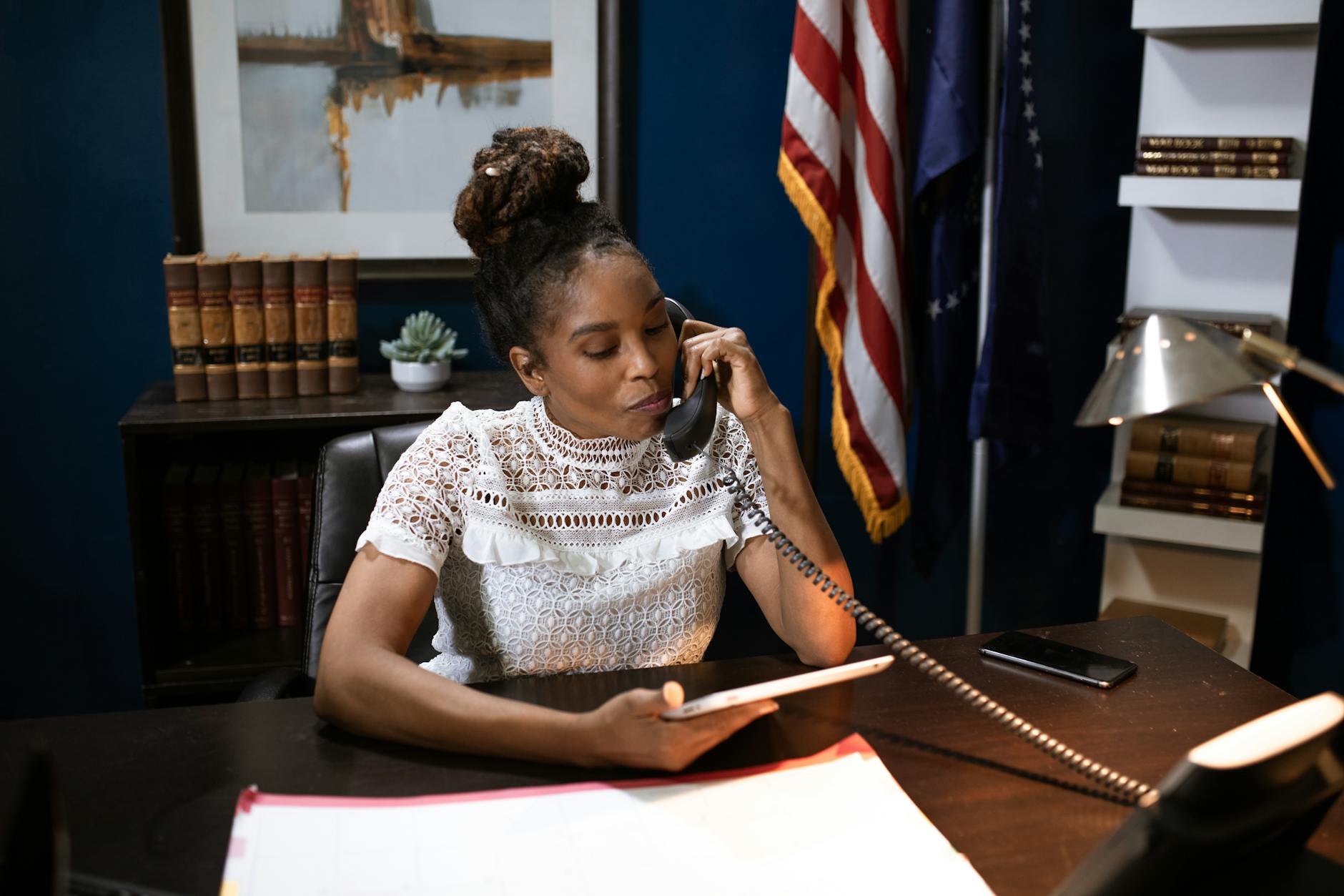 a woman in white shirt sitting on a chair while talking on the phone