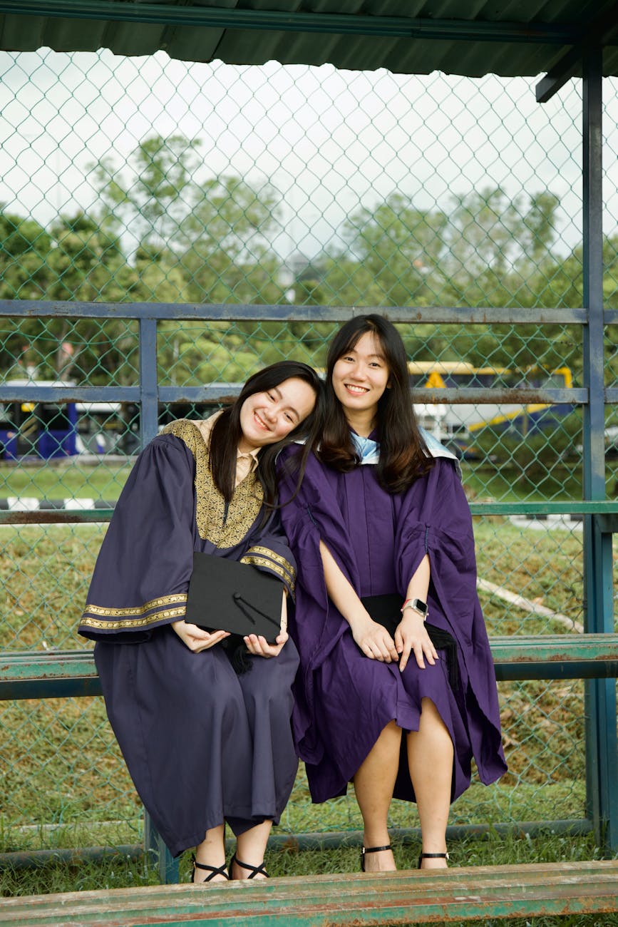 two happy graduates in cap and gown outdoors