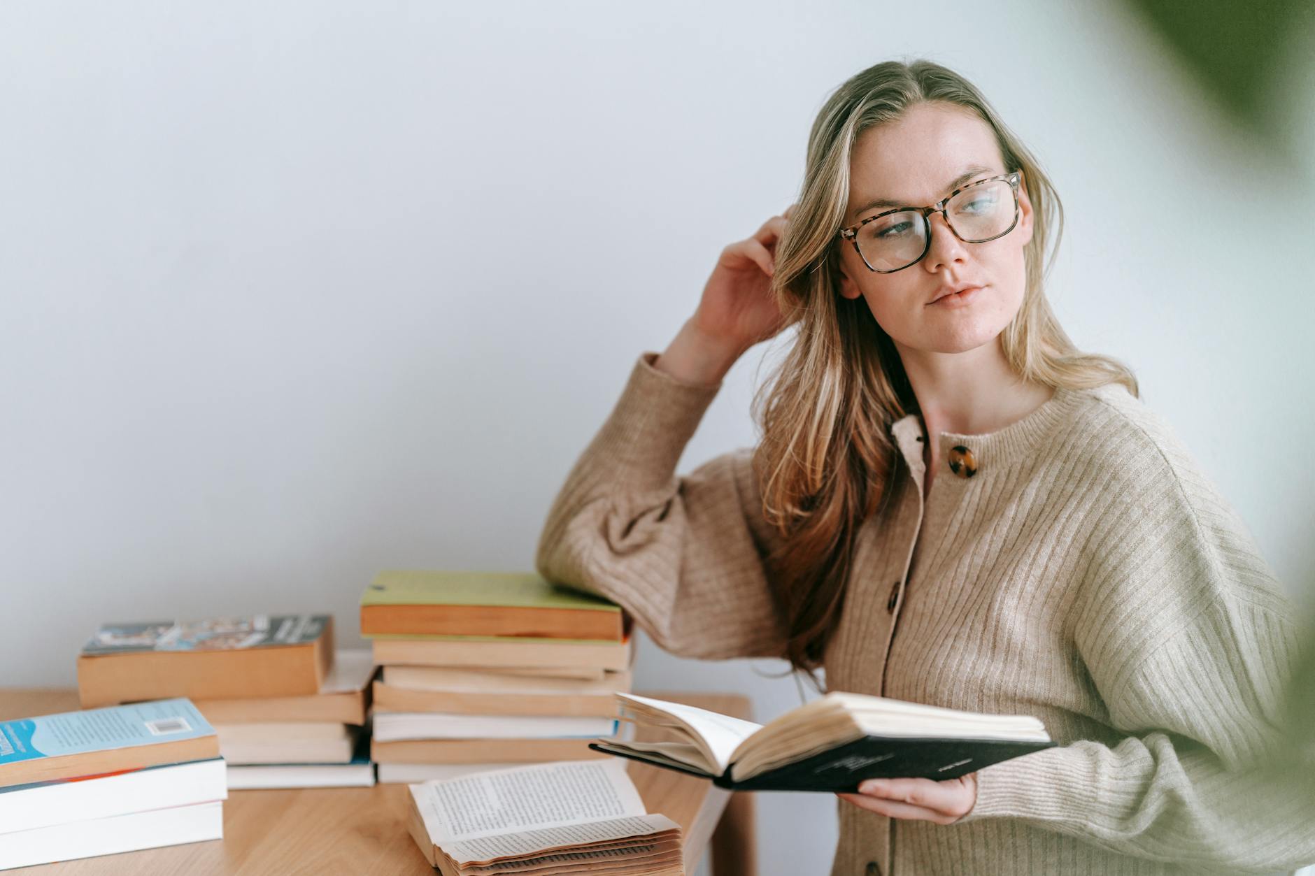 clever woman standing with book and looking away in light room