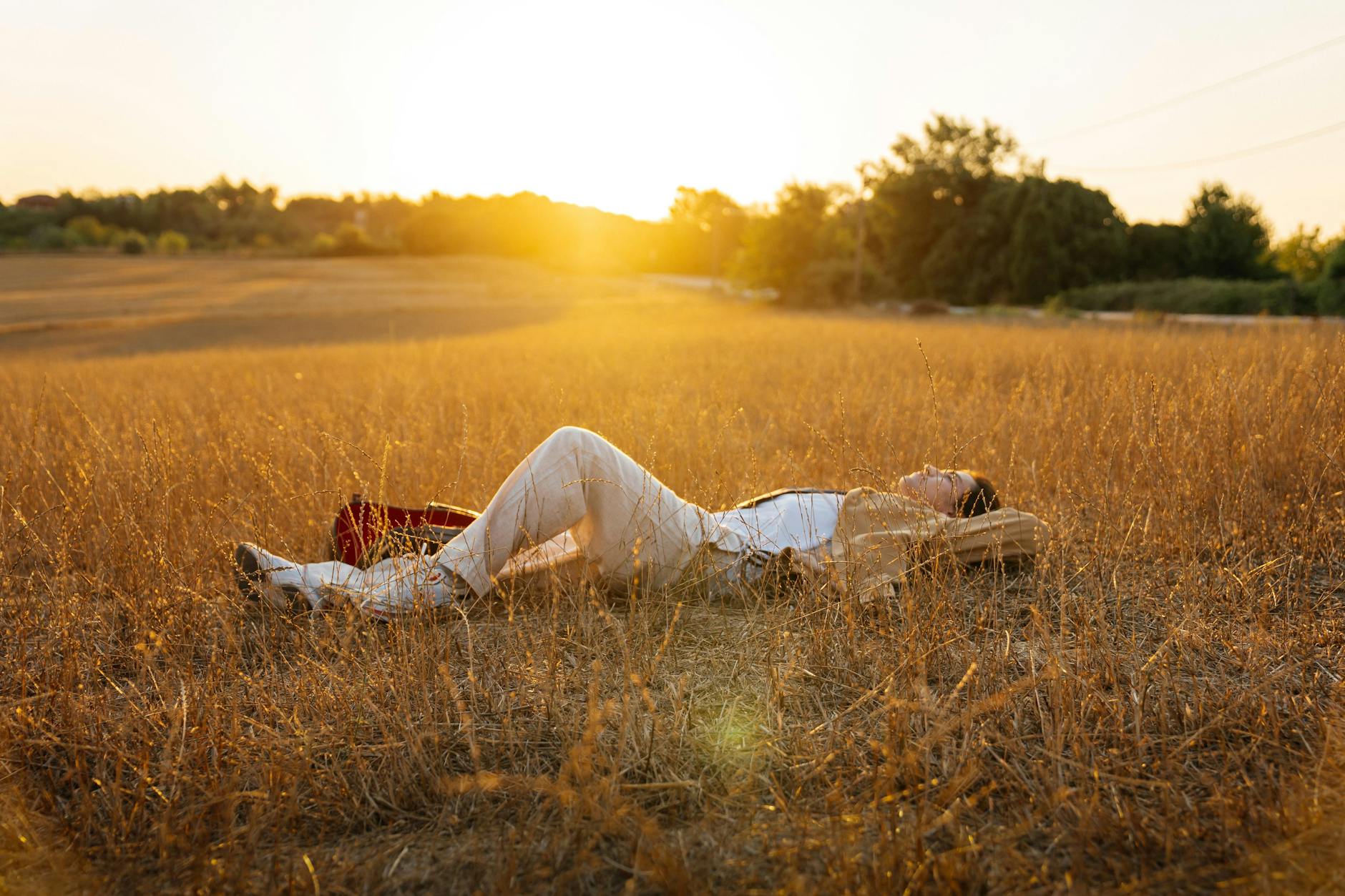 relaxed woman lying in sunny field at sunset