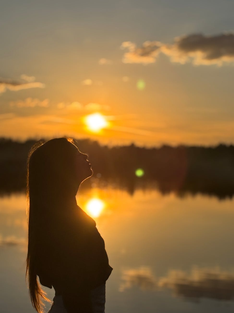 silhouette of woman at sunset by lake