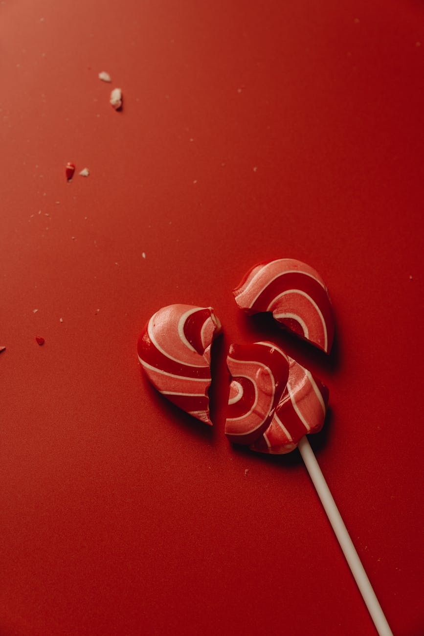 close up photo of a red broken heart shaped lollipop