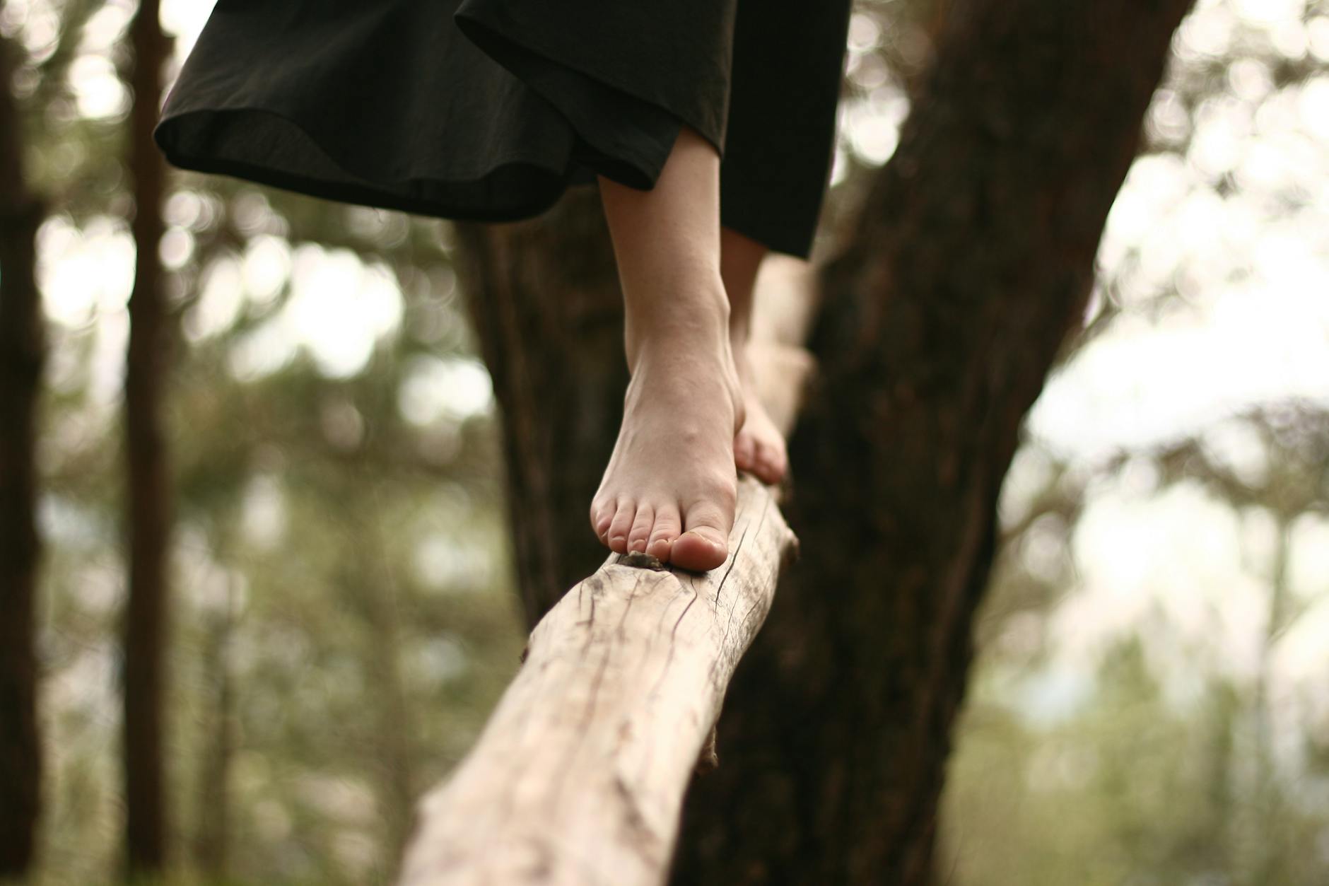 barefoot woman walking on a log