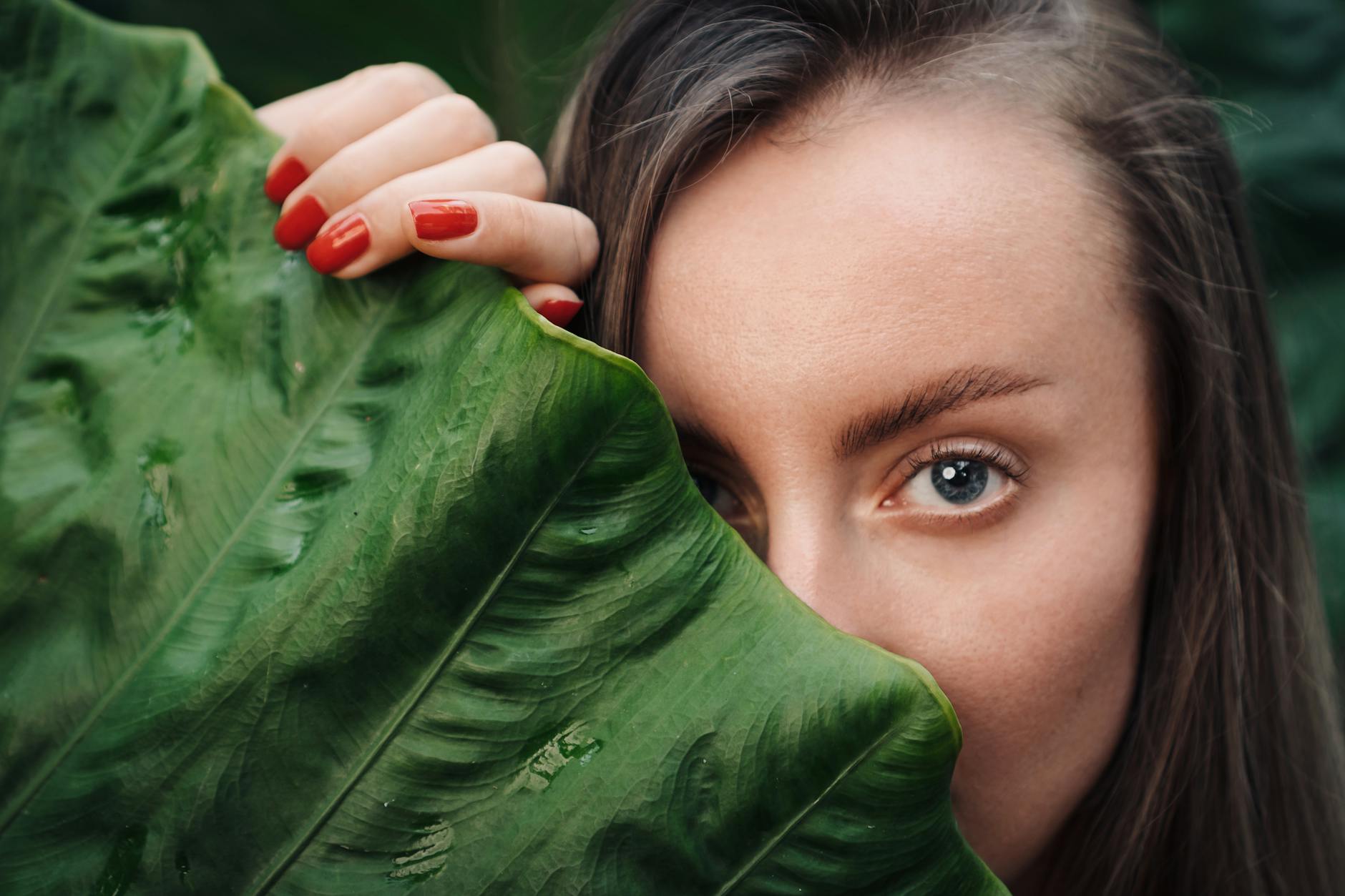 woman covering her face with green leaf