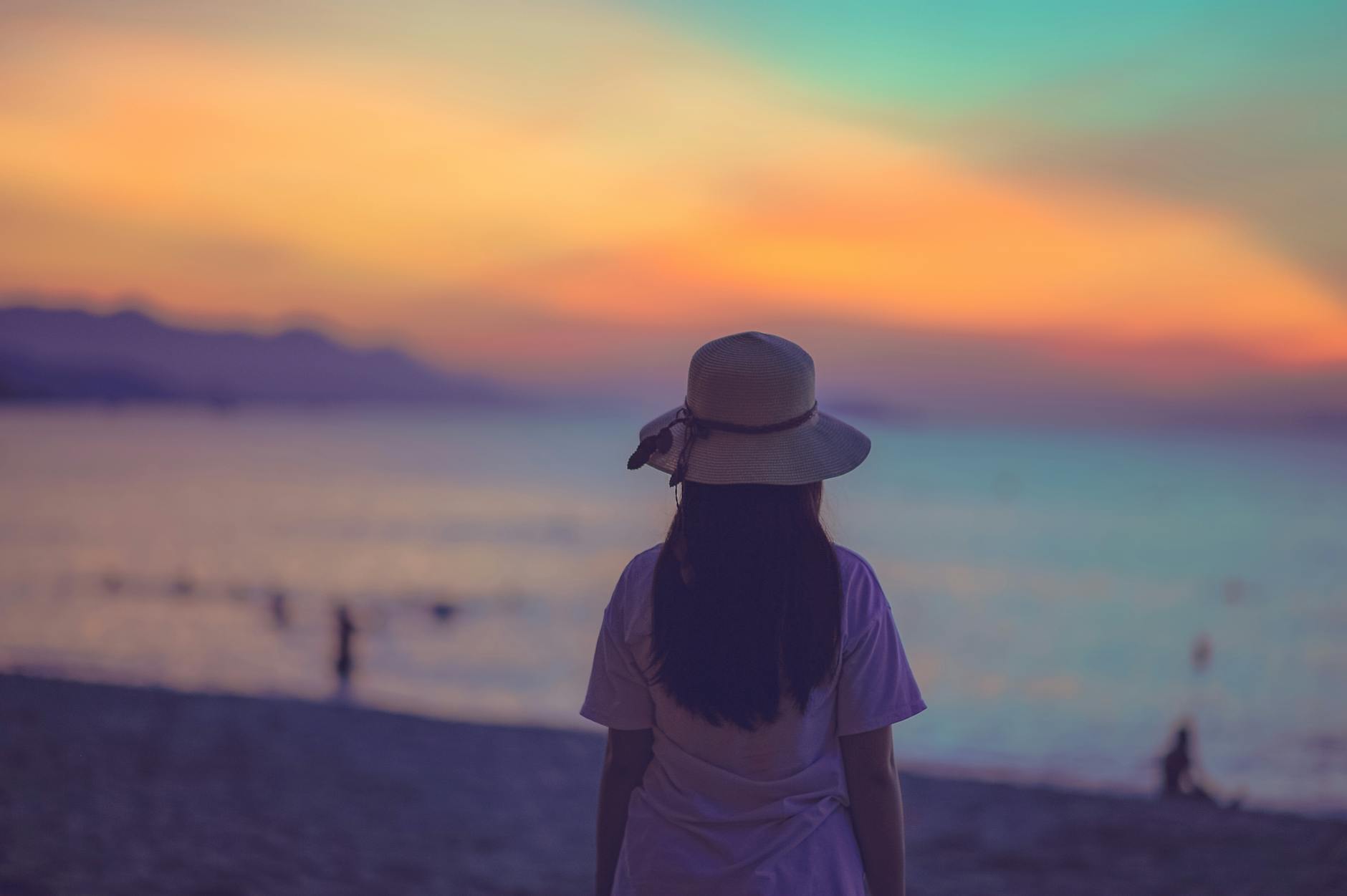 woman in white dress standing near beach during sunset
