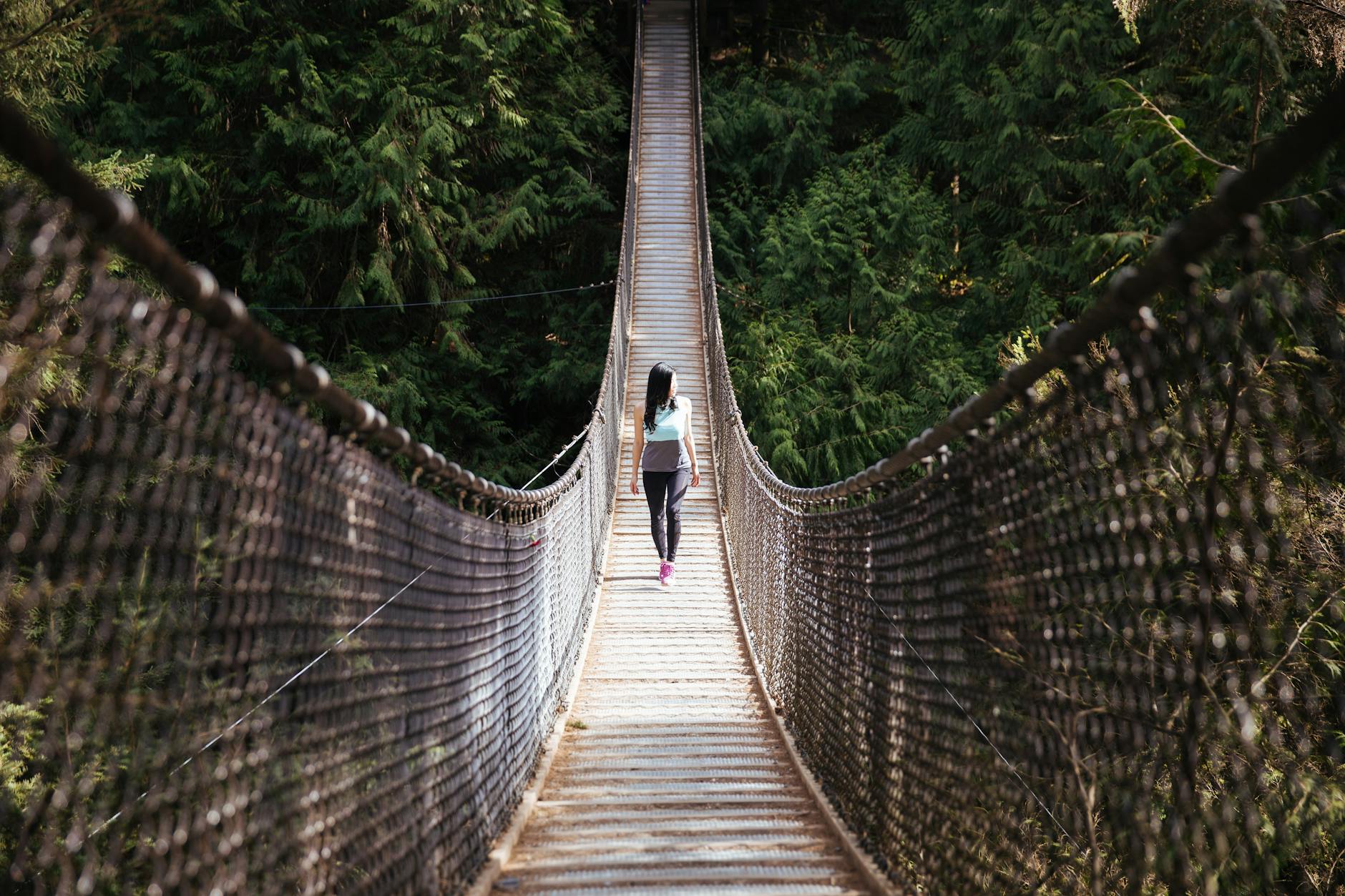 woman wearing blue sleeveless shirt walking on bridge at daytime
