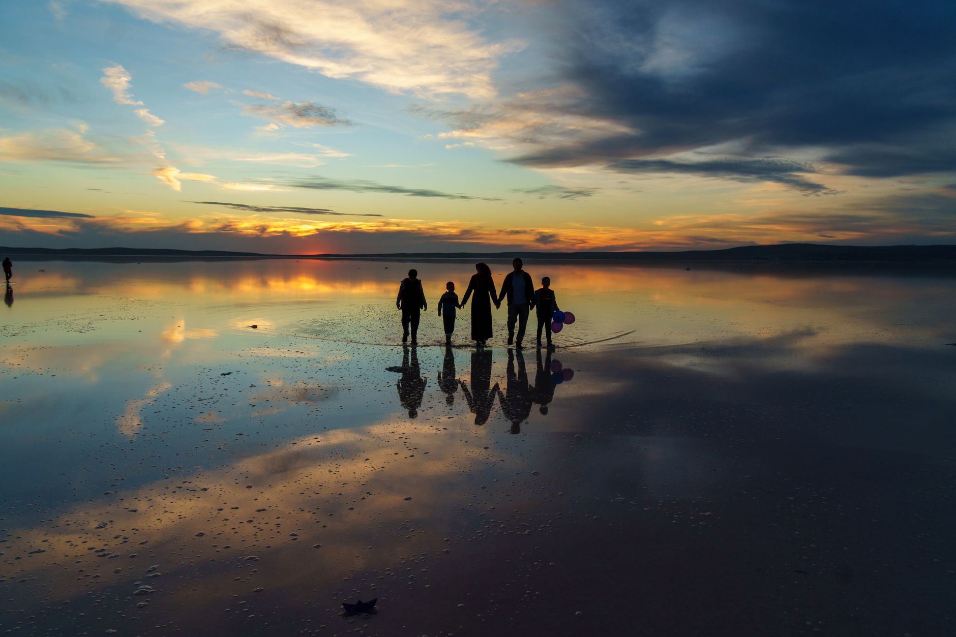 family silhouette at sunset on reflective lake