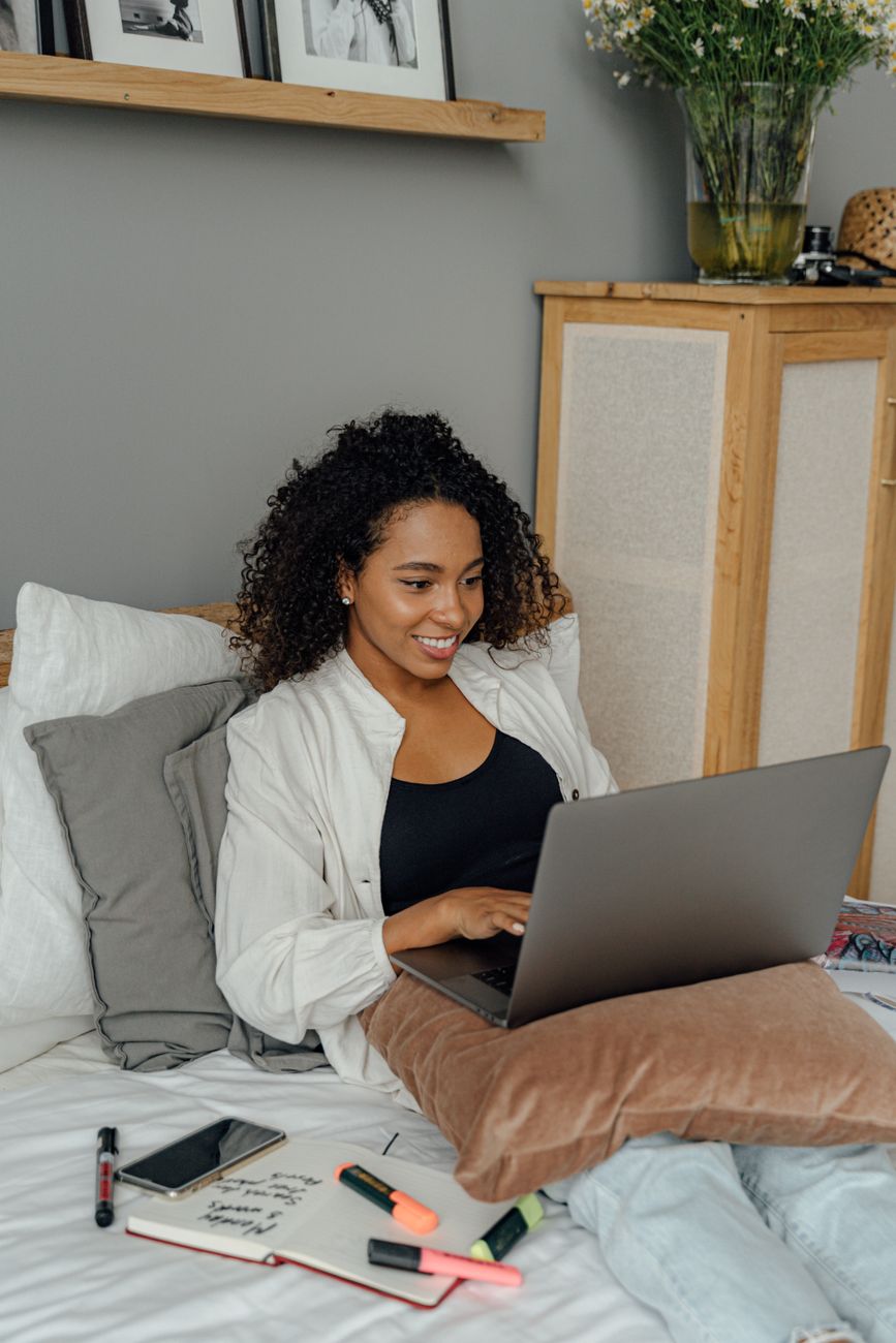 a woman sitting on a bed using laptop