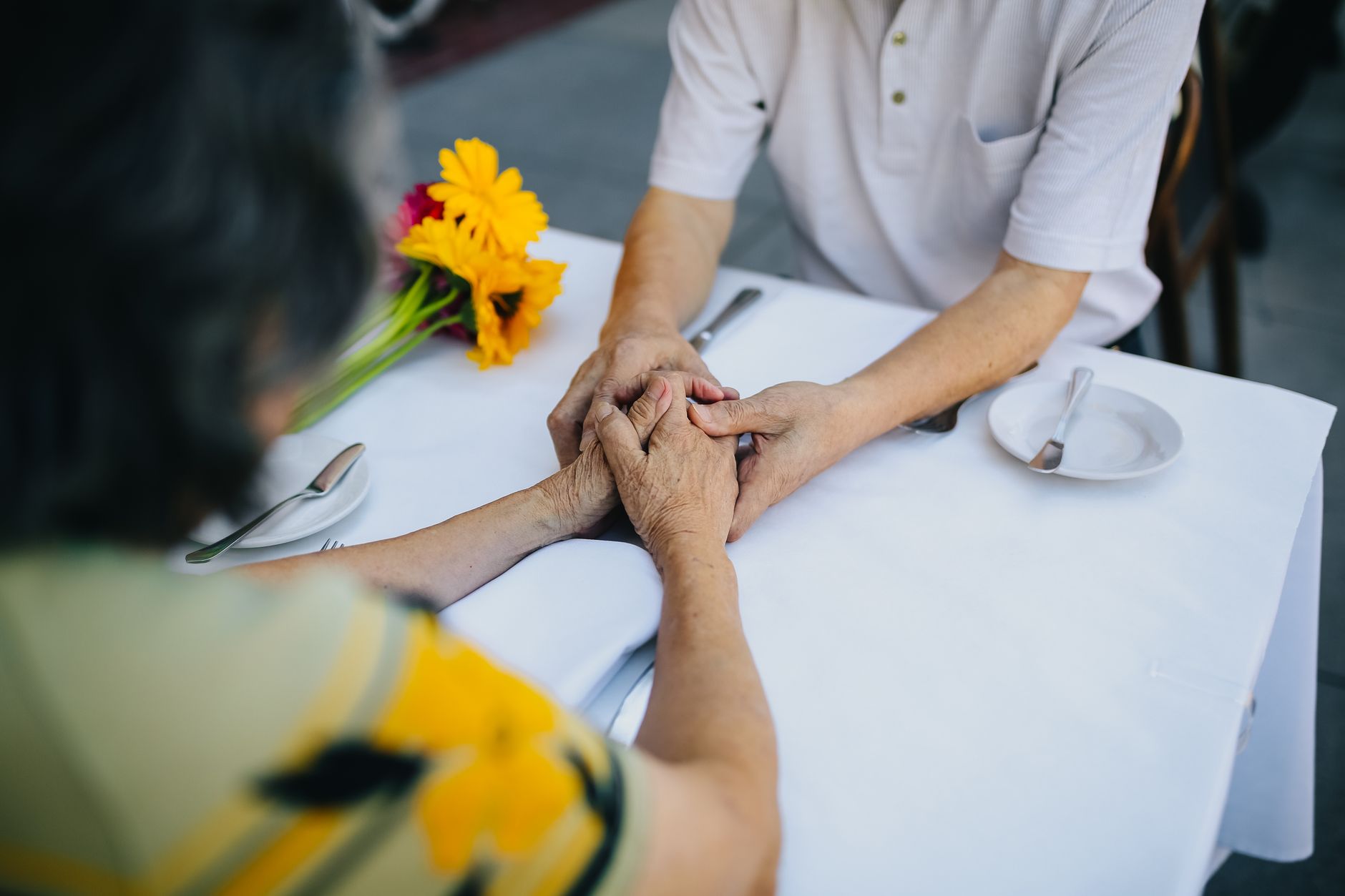 elderly couple holding hands on the table