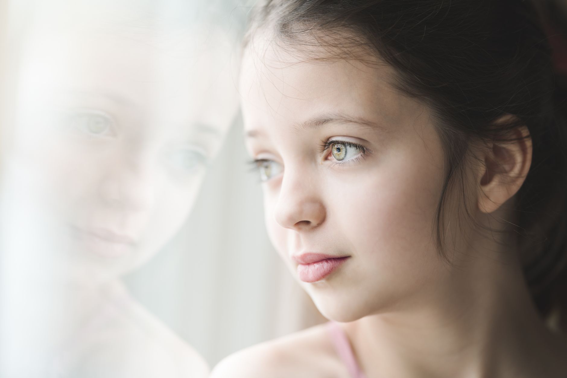 pensive girl with bright eyes looking at window
