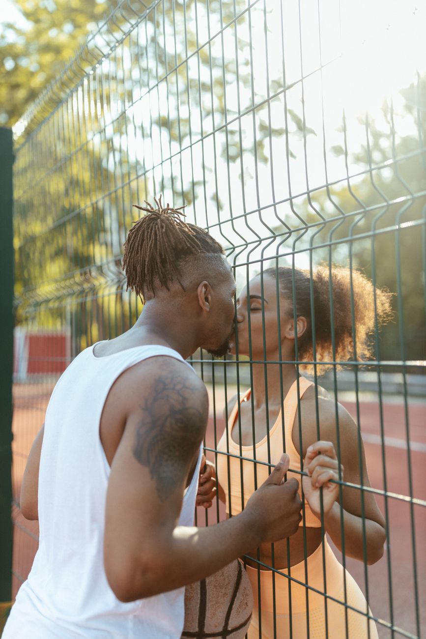 man kissing a woman behind the fence